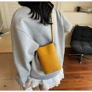 Detail of yellow lychee pattern leather bucket bag with cross-stitch and thin strap