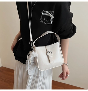 Close-up of beige PU leather shoulder bag with decorative lace and pearl charm detail