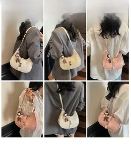 Detailed views of the half-moon crossbody bag in cream and pink with a cute doll charm