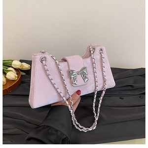 Détail du sac baguette rose en daim avec boucle nœud argentée et bandoulière chaîne