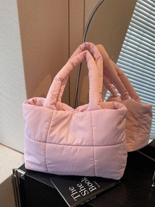 Sac fourre-tout matelassé rose avec texture carrée et larges anses sur surface noire