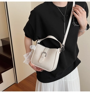 Detail of off-white PU shoulder bag featuring a buckle strap and delicate white lace bow