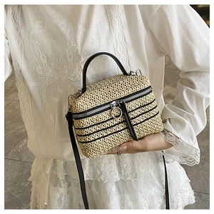 Détail du sac bandoulière en paille tissée avec rayures noires et zip à anneau métallique