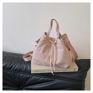 Detail view of pink nylon bucket bag featuring a drawstring closure and side pocket