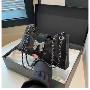 Détail du sac à bandoulière noir avec nœud argenté dans un coffret cadeau de luxe