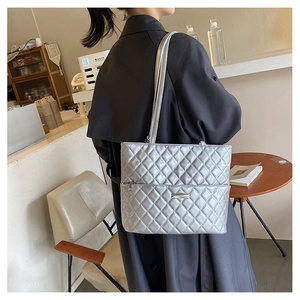Detail of silver quilted tote bag showing rhombus texture on grey trench coat