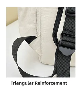 Detail showing triangular reinforced stitching on the straps of the cream travel backpack