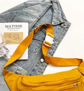 Detail of yellow nylon crossbody bag with adjustable strap and buckle on art background