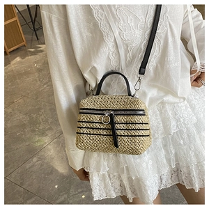 Détail d'un sac bandoulière tissé main avec poignées noires et bandoulière sur le mannequin