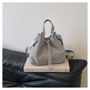 Detail view of the drawstring closure and adjustable strap on the nylon bucket bag