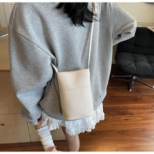 Borsa a tracolla minimalista beige in pelle martellata indossata con outfit casual