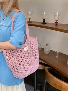 Sac à main en crochet rose avec design ajouré et larges bandoulières pour les vacances
