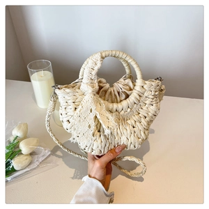 Detail of a semi-circular straw beach bag with cream lace bow and drawstring inner bag