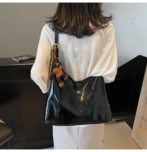 Detail of black glossy tote bag featuring a moon shape and cute character pendant