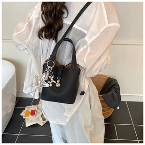 Detalle de bolso tipo cubo en cuero negro con colgantes de estrella y correa ajustable