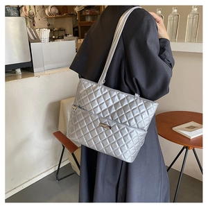 Modern metallic silver quilted tote bag styled with a black coat in a cafe setting