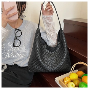 Close-up of black leather woven tote bag showing luxury v-pattern craftsmanship