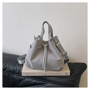 Detail of grey nylon drawstring bucket bag with sturdy handles and adjustable shoulder strap