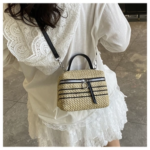 Détail d'un sac à bandoulière en paille tressée avec rayures noires et anneau zippé