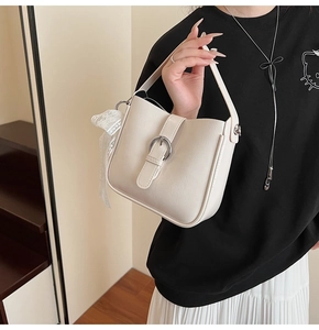 Detail of off-white leather shoulder bag with metal buckle and lace ribbon bow decoration