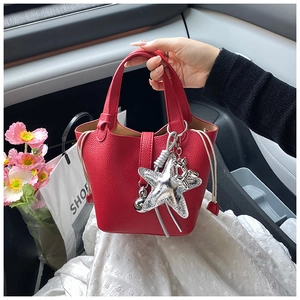 Detalle de bolso tipo cubo en cuero rojo con grabado de lichi y colgante de estrella