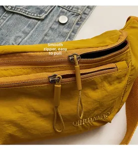 Detail der gelben Nylon-Brusttasche mit Doppelreißverschluss und Logo-Stickerei
