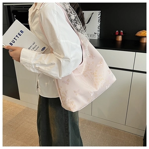 Détail du sac à bandoulière rose brodé avec bords en dentelle et motifs de papillons