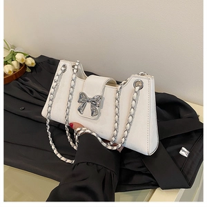 Détail du sac baguette blanc perle avec nœud, chaîne argentée et cuir mat de haute qualité