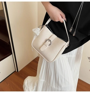 Detail of cream white handbag with silver buckle and delicate lace bow accent