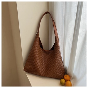 Detailed view of brown woven tote bag with smooth strap in a bright sunlit setting