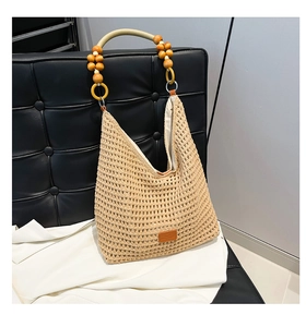 Detail of hollow knit tote bag with wooden beads and green handle on leather background