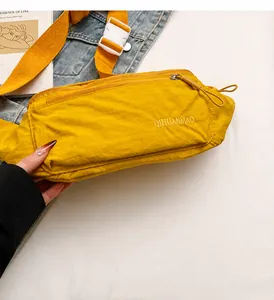 Detail of yellow nylon crossbody bag featuring secure zipper and brand logo text
