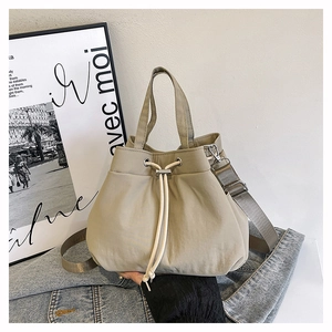Detail of khaki nylon drawstring bucket bag with adjustable wide shoulder strap and metal eyelets