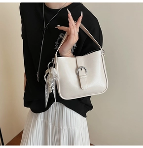 Close-up of off-white leather handbag with silver buckle and pearl lace charm detail