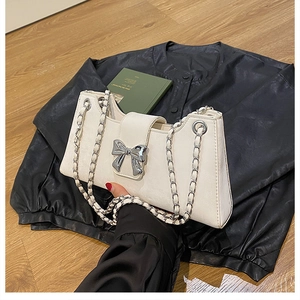 Vue détaillée du sac à bandoulière en cuir blanc avec boucle nœud argenté et chaîne