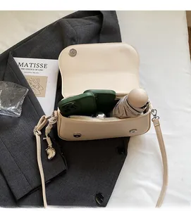 Vue intérieure montrant la capacité du sac bandoulière en cuir crème avec accessoires