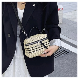 Photo de mode d'un sac bandoulière en paille beige avec finitions en cuir noir