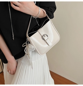 Detail of cream shoulder bag with silver buckle and lace pearl bow charm accessory