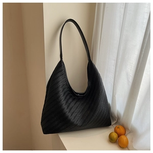 Detail of black woven leather tote bag with V-shaped texture in a bright room setting