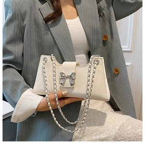 Détail du sac baguette ivoire avec boucle nœud argenté et bandoulière en chaîne