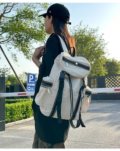 Outdoor model shot of an off-white multi-pocket techwear backpack with nylon fabric