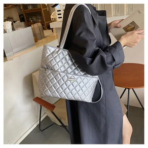 Close-up of a silver quilted tote bag with metallic finish and exterior zipper pocket