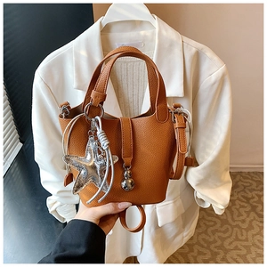 Detalle del bolso tipo cubo en cuero marrón con diseño de lichi y colgante de estrella