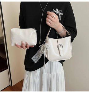 Detail of cream shoulder bag set featuring delicate lace bow and pearl pendant charm