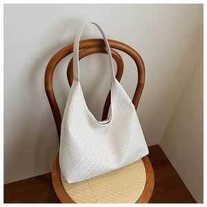 Detail of white woven hobo tote bag with herringbone texture on vintage wooden chair