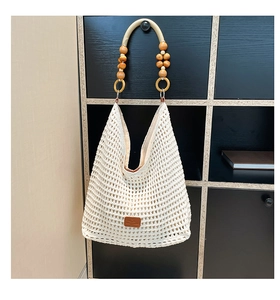 Detail of white hollow crochet tote featuring wooden bead handles and leather patch