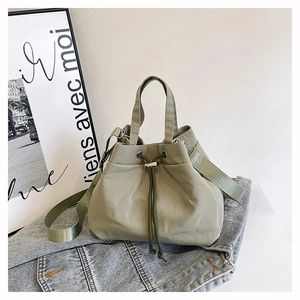 Detail of sage green drawstring bucket bag made of lightweight nylon with adjustable strap