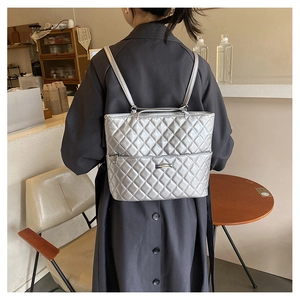 Detailed back view of a silver quilted diamond pattern backpack on a model in a cafe