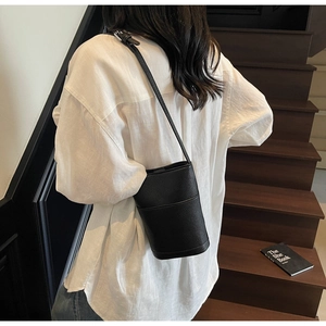 Detailed back view of a black lychee texture leather bucket bag with a slim strap