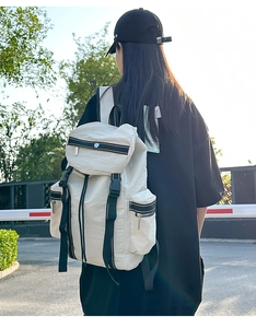 Close-up of ivory hiking backpack with buckled flap and adjustable straps on a model